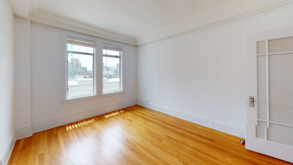 an empty living room with wood floors and a window