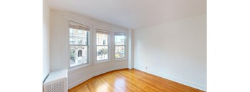 an empty living room with three windows and wood floors