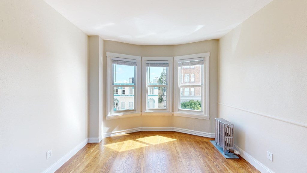 an empty living room with three windows and a wood floor