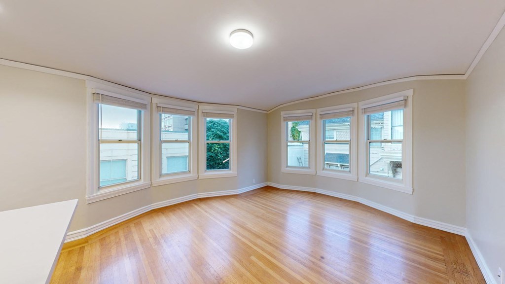 an empty living room with wood floors and bay windows