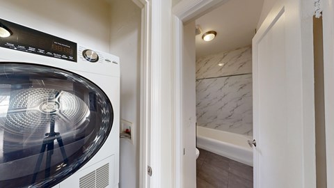 A washing machine is in a small room with a door open.