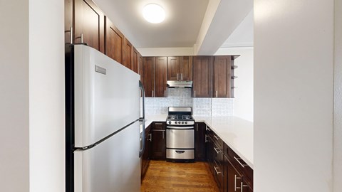 A kitchen with a refrigerator on the left and a stove top oven on the right.