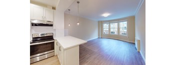 an empty kitchen and living room with white cabinets