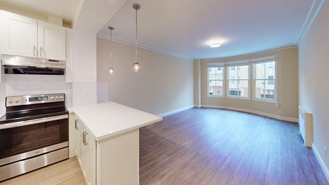 an empty kitchen and living room with white cabinets