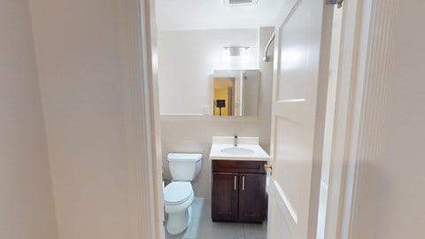 A bathroom with a toilet, sink, and mirror.