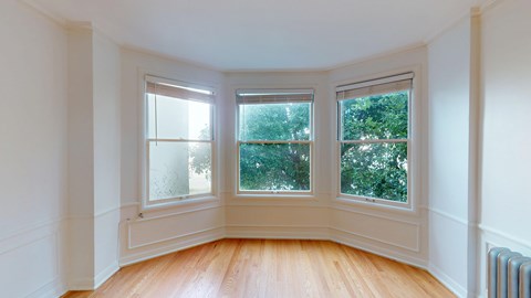 A room with a wooden floor and three windows.
