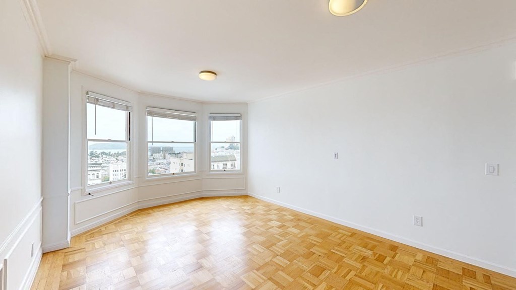 an empty living room with wood flooring and a window