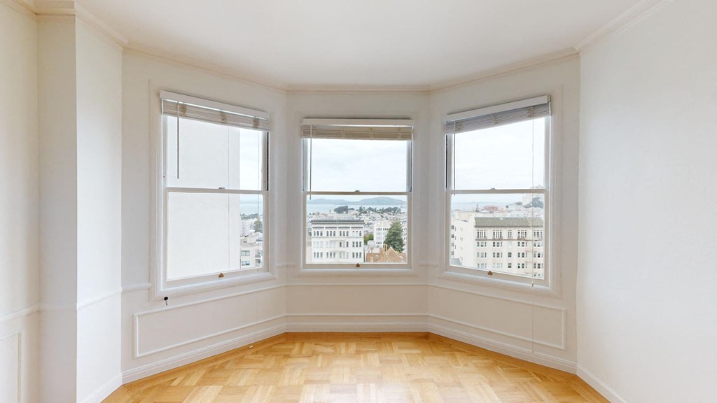 a living room with three windows and a wooden floor