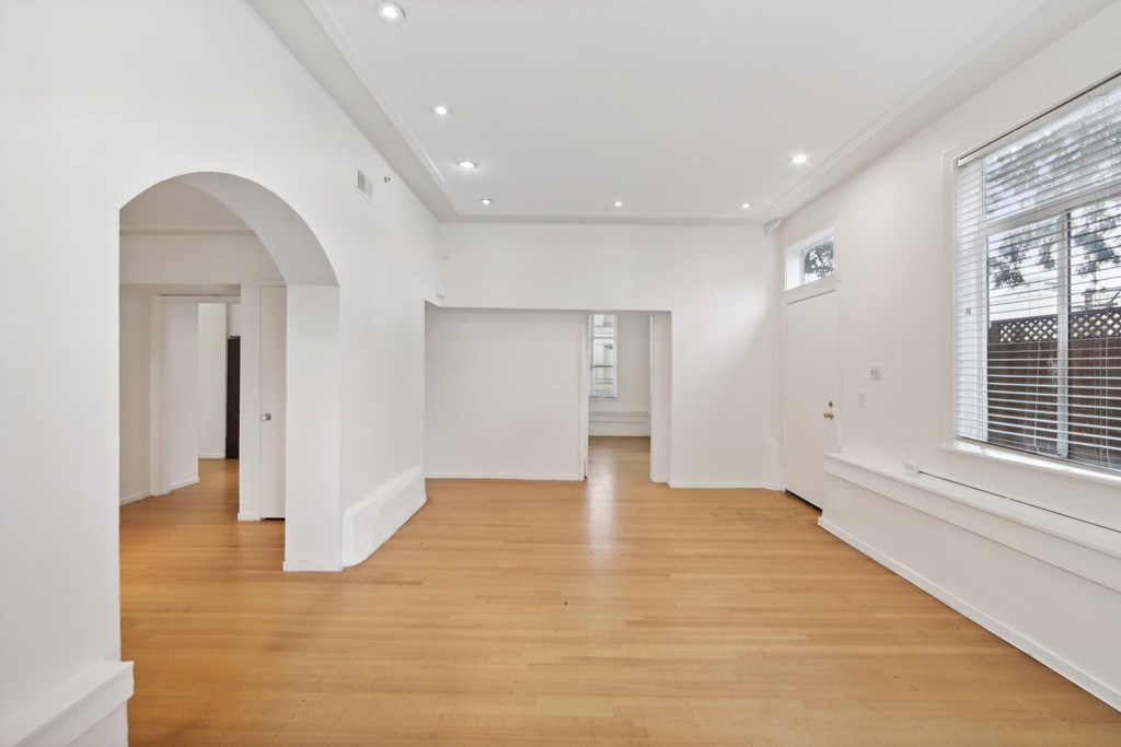A spacious room with wooden floors and white walls.