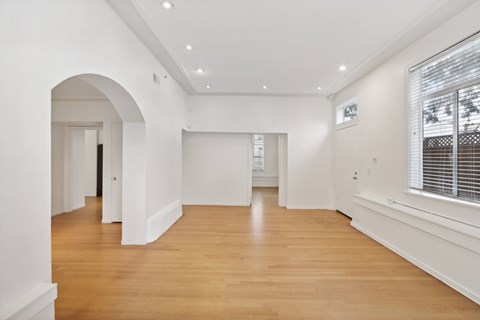A spacious room with wooden floors and white walls.