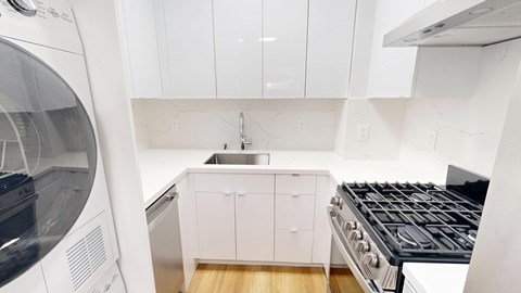 A modern kitchen with white cabinets and a black stove top.