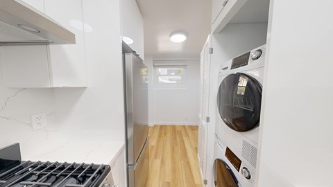 A white kitchen with a refrigerator, oven, and washing machine.