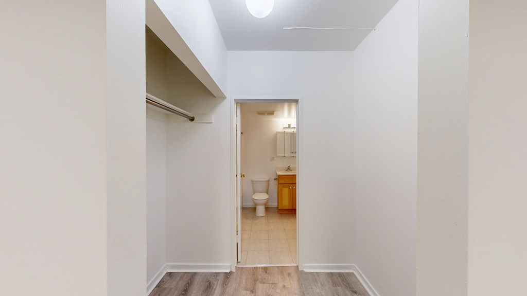 A white hallway with a doorway leading to a bathroom.