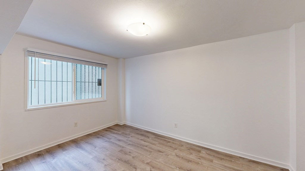 A room with a window and wooden flooring.