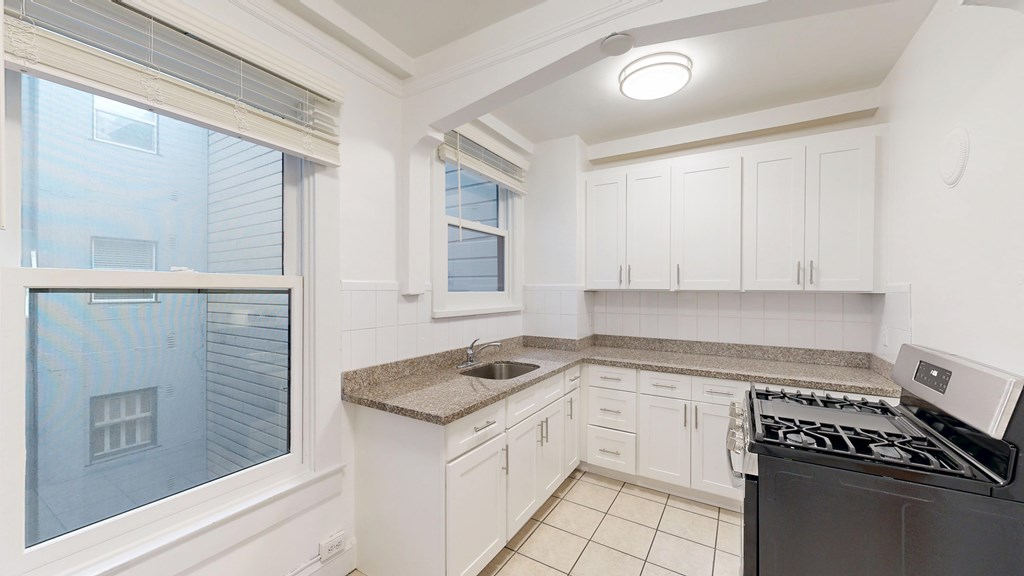 A kitchen with white cabinets and a black stove top oven.