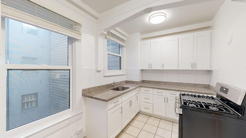 A kitchen with white cabinets and a black stove top oven.