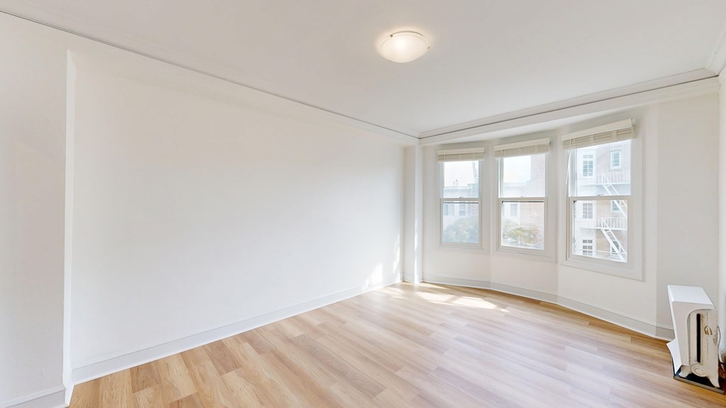A room with a white wall and a window with a white frame.