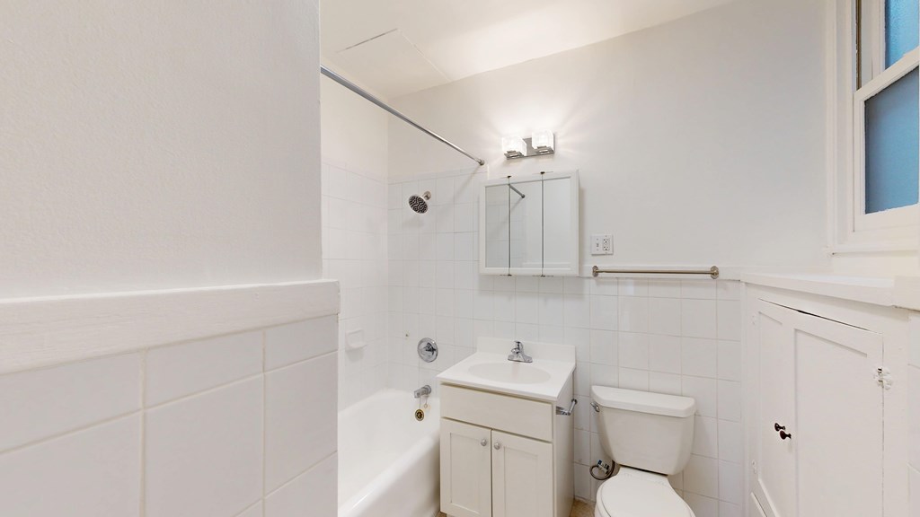 A white bathroom with a toilet, sink, and bathtub.