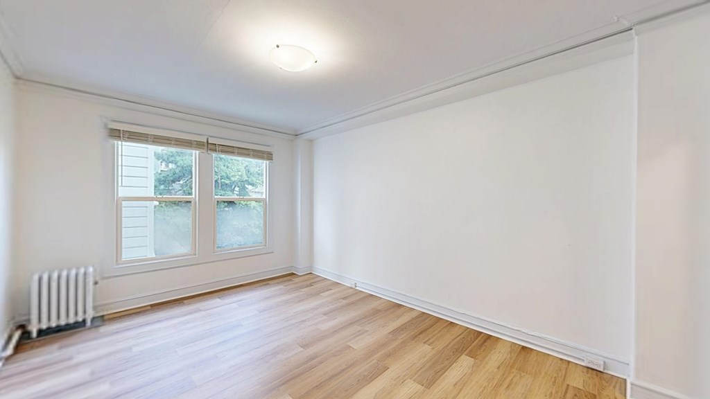 A room with a window and a radiator on the floor.