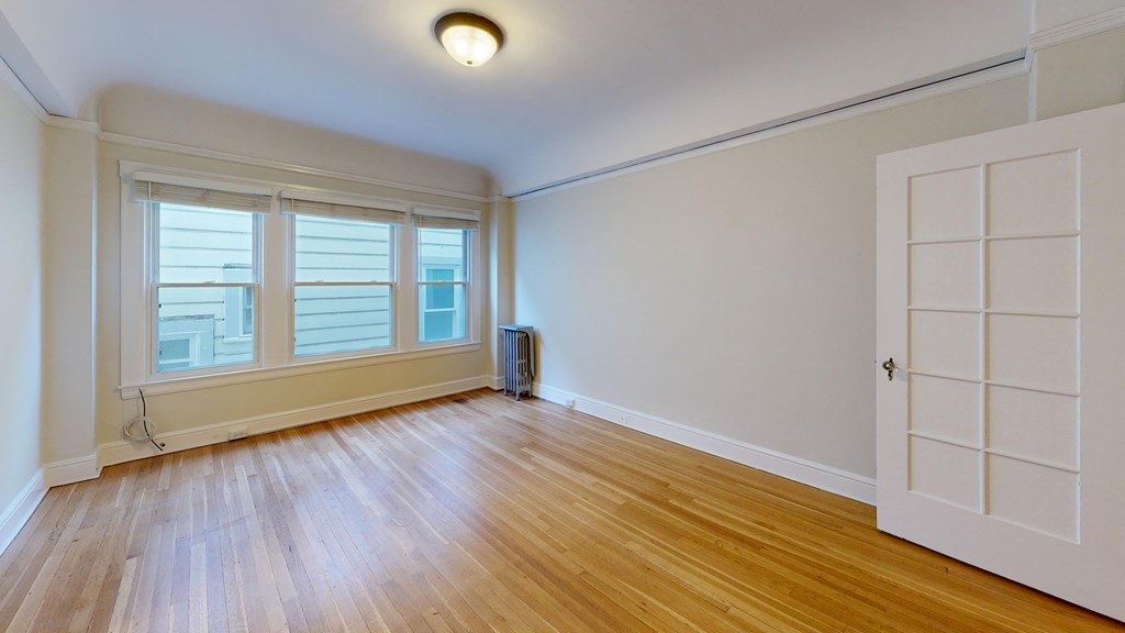 an empty living room with wood floors and a white door and window