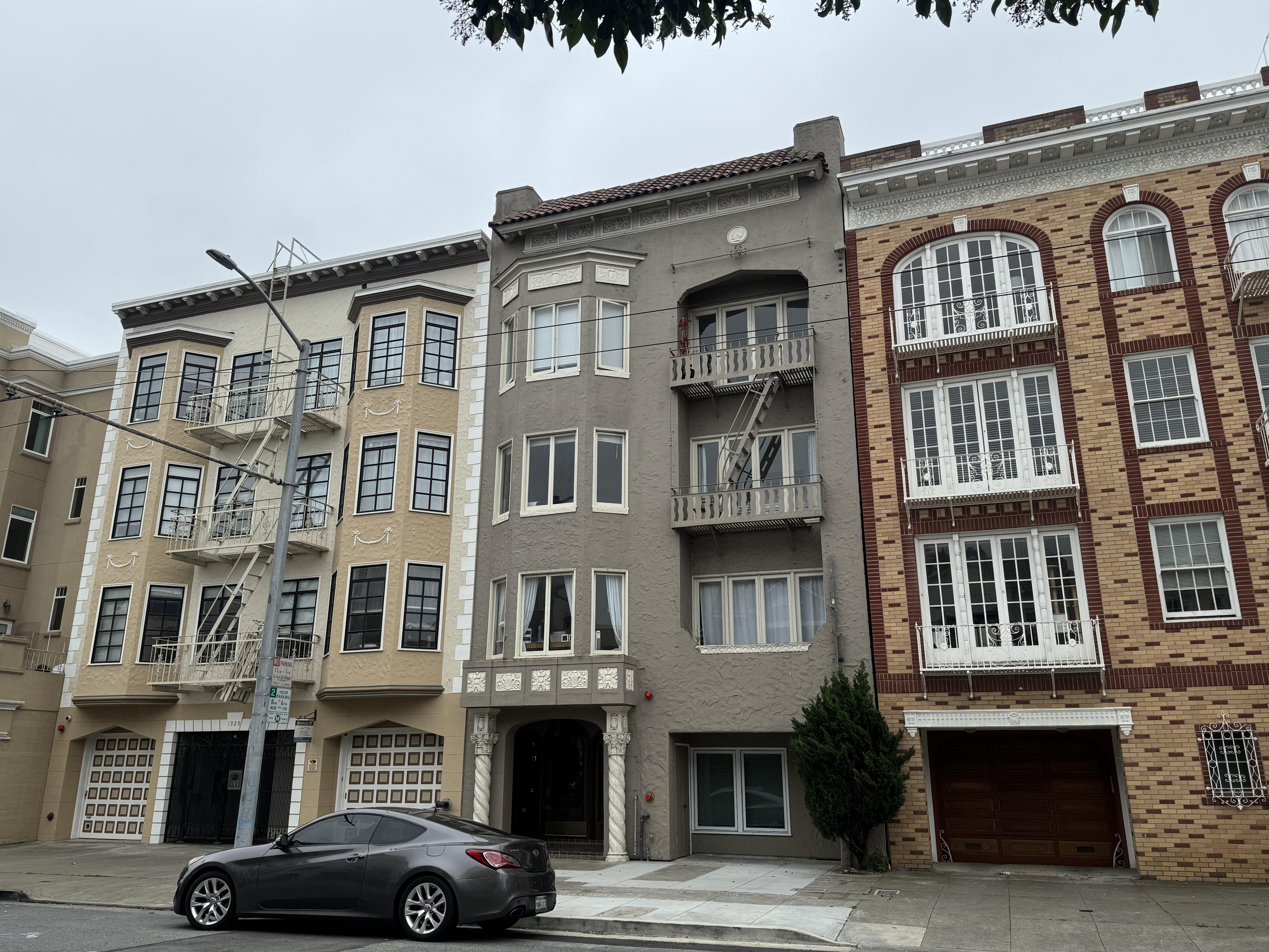 A grey car is parked in front of a building.