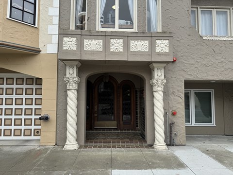 A building with a brown and white facade has a large arched doorway.
