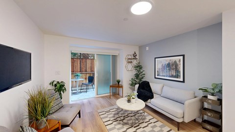 A living room with a white couch, a coffee table, and a TV on the wall.