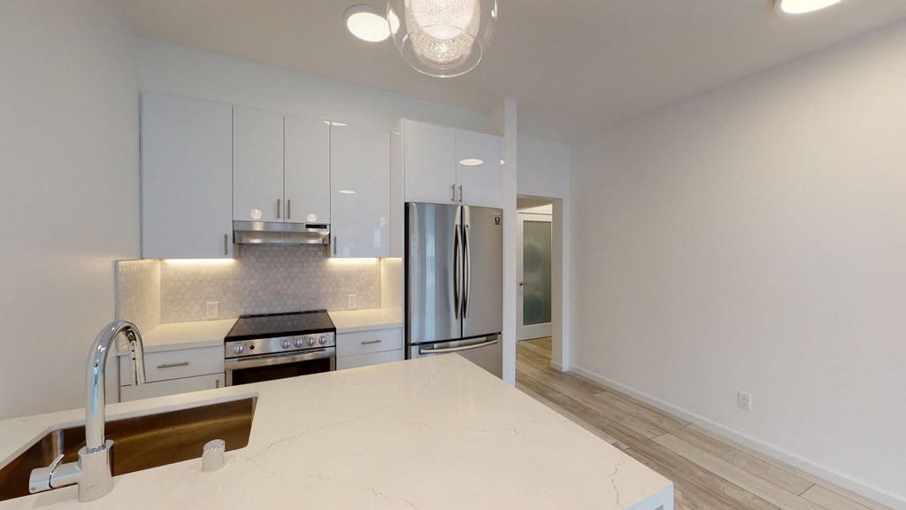 Kitchen with multiple cabinets, refrigerator, stove, range hood, and sink