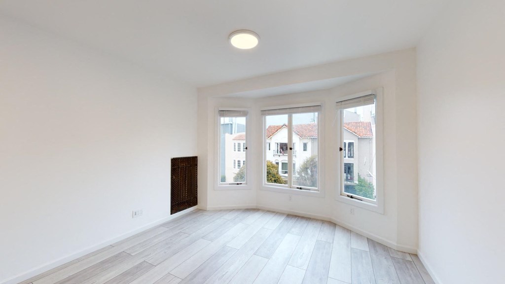 Sunlit room with a large window and a wood-like flooring Sunlit room with a large window and a wood-like flooring