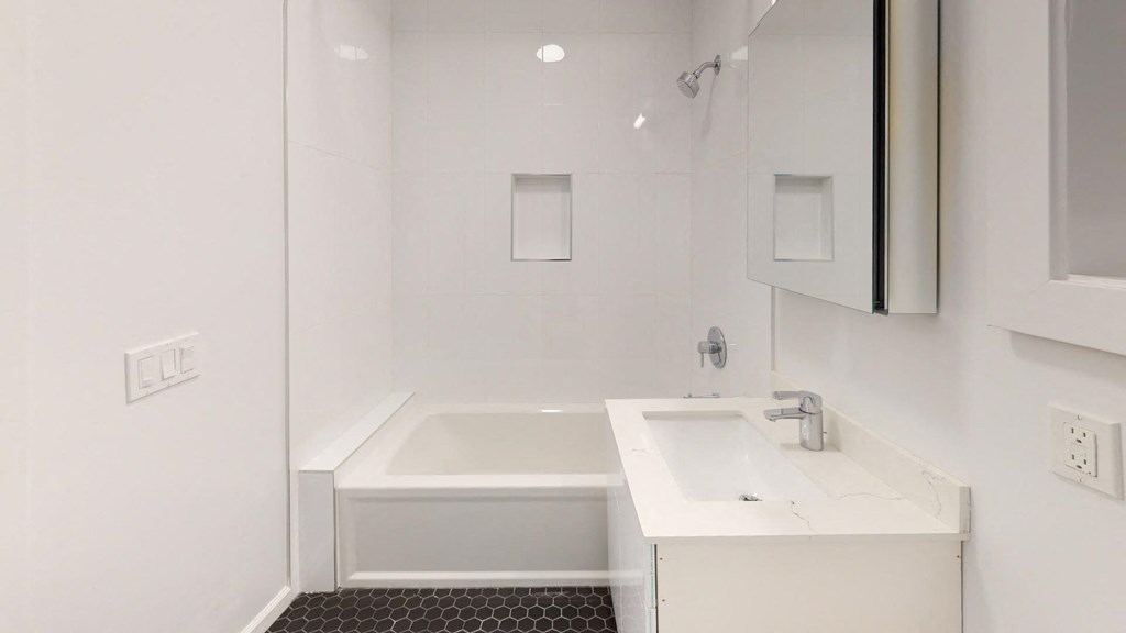 a white bathroom with a sink and a bath tub