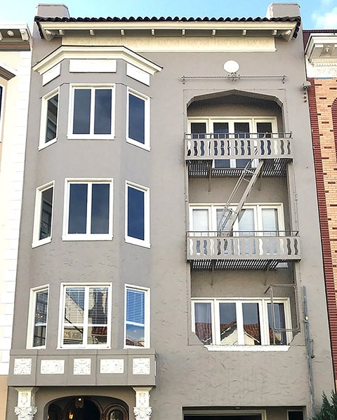 an apartment building with two balconies and a fire escape