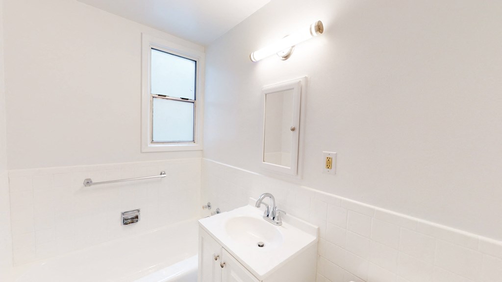 a white bathroom with a sink and a window