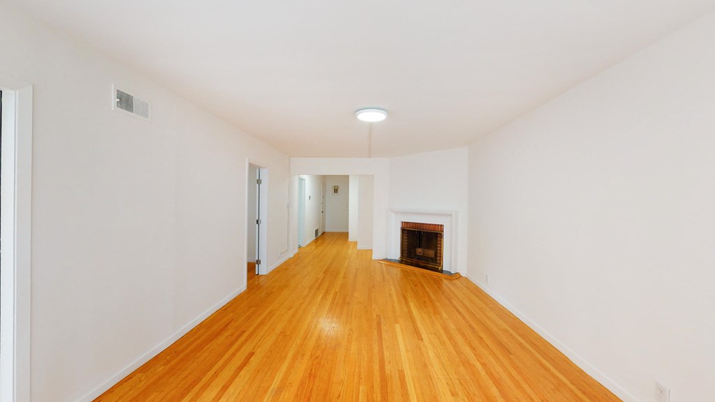 a living room with white walls and a fireplace and wooden floors