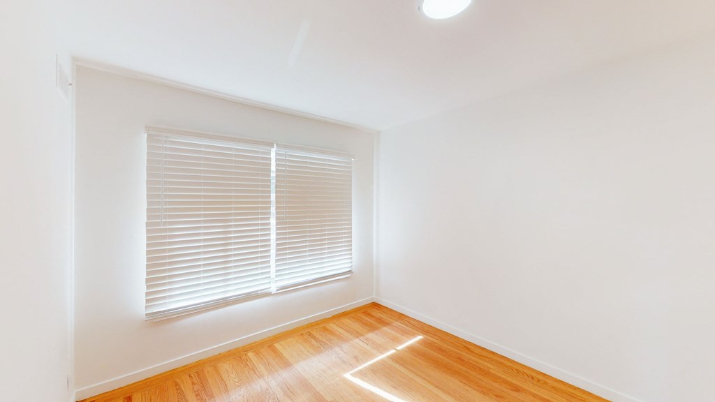 an empty room with a window and wood floors