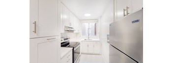 a white kitchen with stainless steel appliances and white cabinets