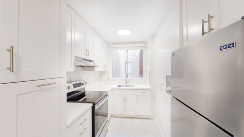 a white kitchen with stainless steel appliances and white cabinets