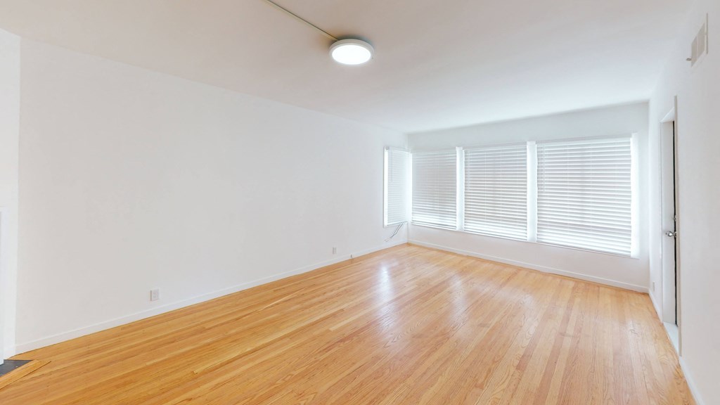 an empty living room with wood floors and white walls