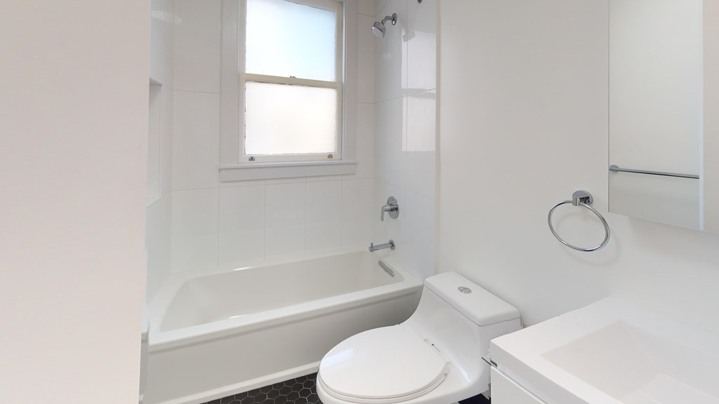A white bathroom with a toilet, sink, and bathtub.