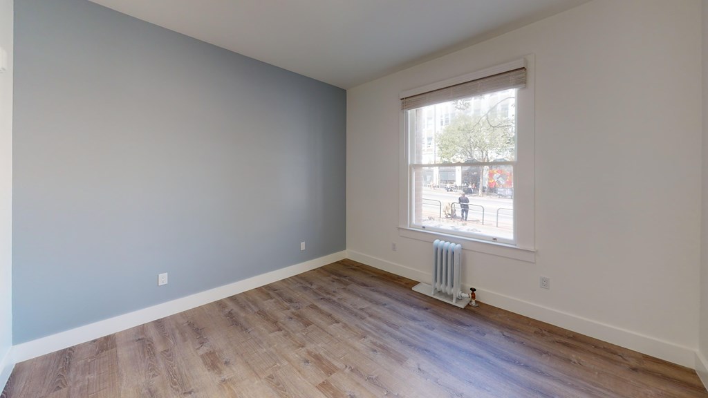 A room with a window and a radiator on the floor.