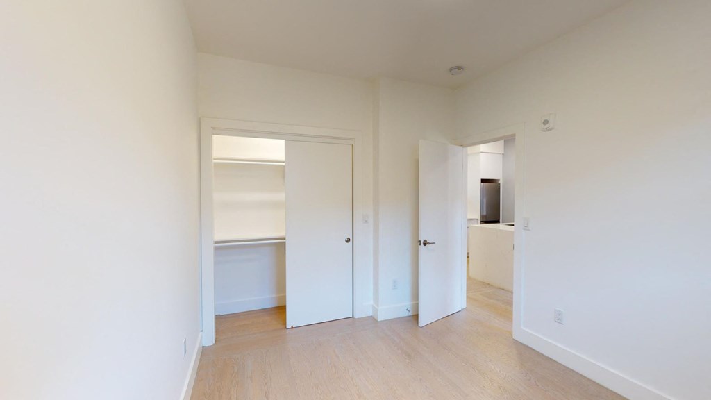 a bedroom with white walls and a door to a closet