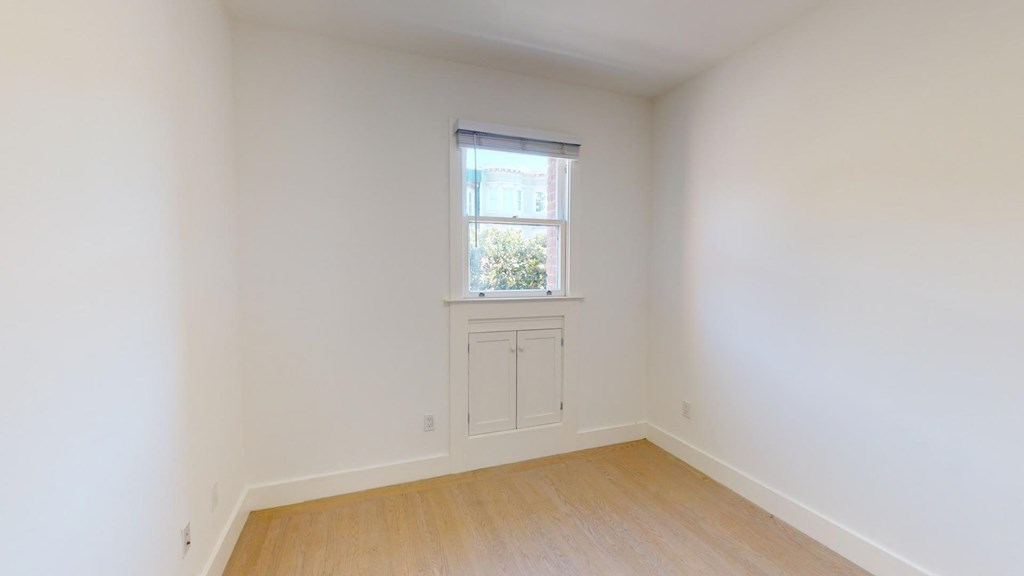 a room with white walls and a window and wooden floors