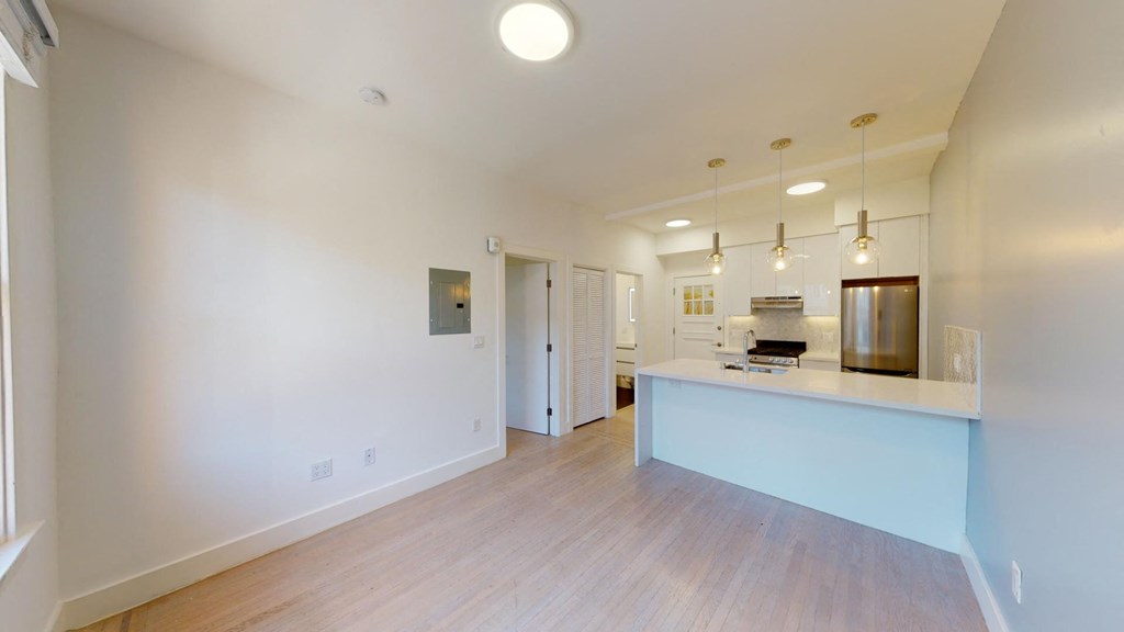 a living room and kitchen with a counter top and a door to a hallway