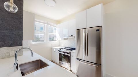 a white kitchen with stainless steel appliances and a sink