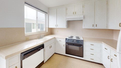 a kitchen with white cabinets and a stove and a window
