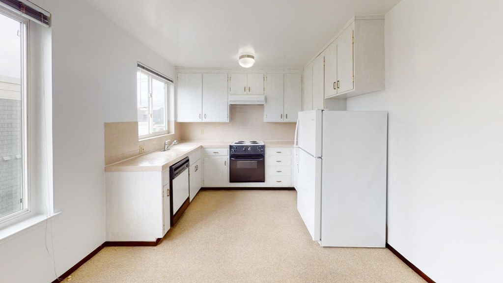 an empty kitchen with white cabinets and white appliances
