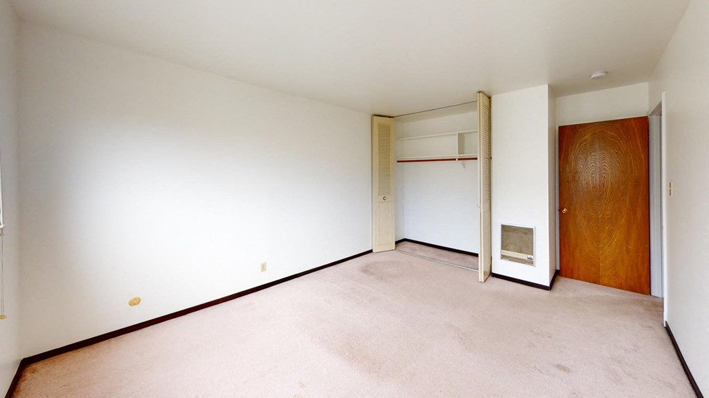a empty room with white walls and a wooden closet