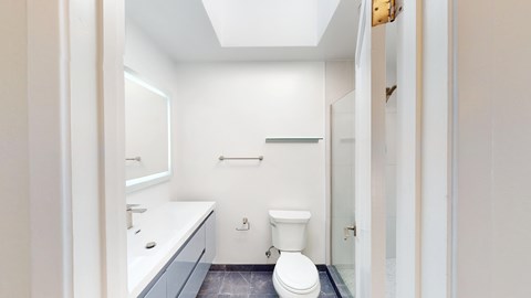 A white bathroom with a toilet, sink, and mirror.