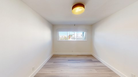 A room with a window and a wooden floor.