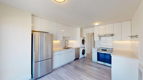 A modern kitchen with a refrigerator, oven, and washing machine.