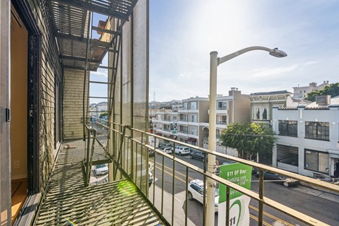 Apartment balcony overlooking a street, parked cars and with a few trees